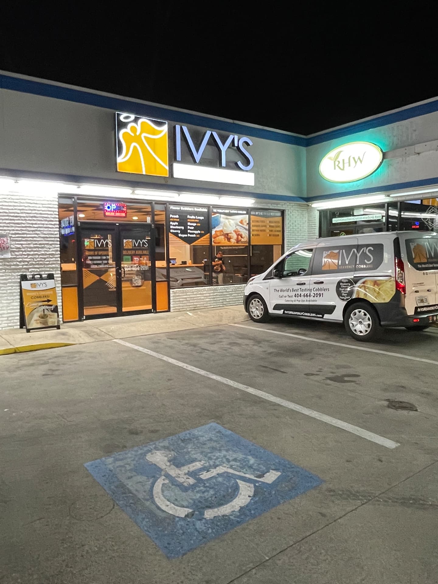 Ivy's Heavenly Cobblers storefront lit at night with the branded delivery van parked outside