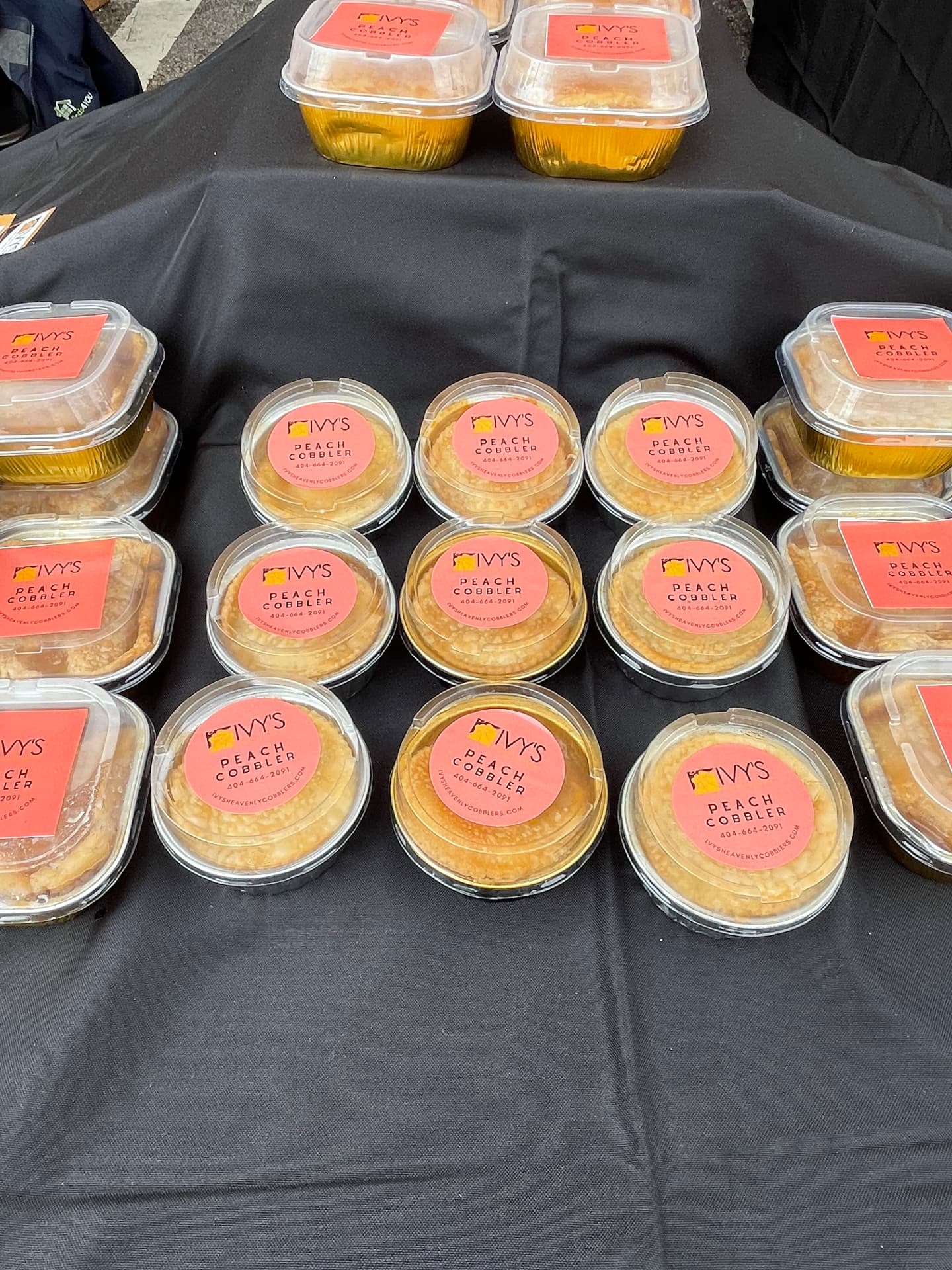 Sealed cups of Ivy's peach cobbler with branded labels on a display table